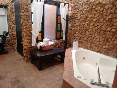 a bathroom with a tub and a stone wall at Hotel Boutique Iguaque Campestre Spa & Ecolodge in Villa de Leyva