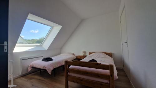 a attic room with two beds and a window at La désirée in Blangy-sur-Bresle