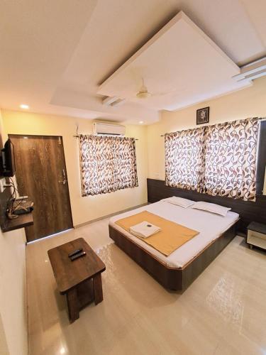 a bedroom with a large bed and a table at Hotel Sai Neelam in Shirdi