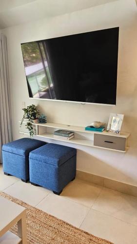 a living room with a large television and a blue stool at Xonadu con dominio in Puerto Plata