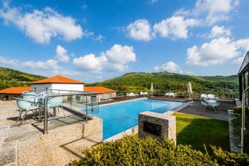 a villa with a swimming pool and mountains in the background at Quinta da Eira do Sol in Guimarães