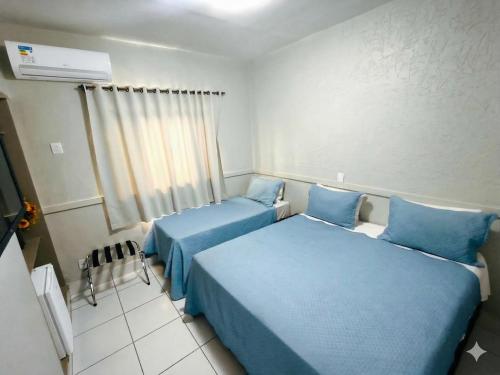two beds in a room with blue sheets at Bandeirantes Hotel in Cuiabá