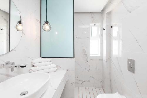 a white bathroom with a sink and a mirror at Elvita beach hotel in Lartos