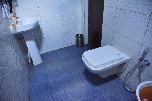 a bathroom with a white toilet and a sink at Hillwoods homestay in Somvārpet