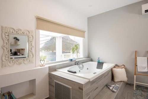 a bathroom with a large white tub and a window at Hyperion Hotel in Myrties