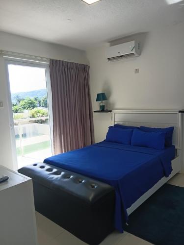 a bedroom with a blue bed and a window at Kingston Condo with Rooftop Pool & Gazebo in Kingston