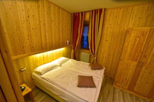 a small bed in a wooden room with a window at Albergo Stelvio in Bormio