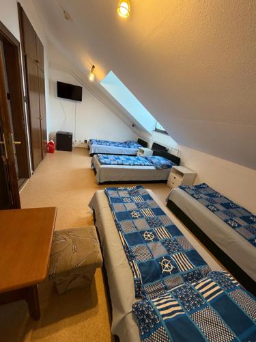 a attic room with three beds and a table at Fenyő Liget Vendégház in Balatonlelle