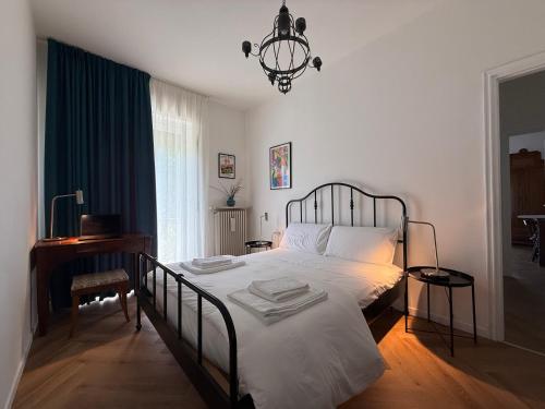a bedroom with a bed with white sheets and a chandelier at Casa Gaudia Varese living-working e quiete in Barasso