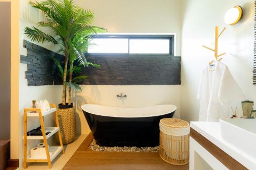 a bathroom with a black and white tub and a palm tree at Palmcove Chiang Mai Old Town in Chiang Mai