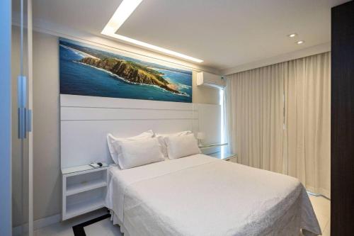 a bedroom with a white bed and a painting on the wall at Estudio232 - Asa Sul in Brasília
