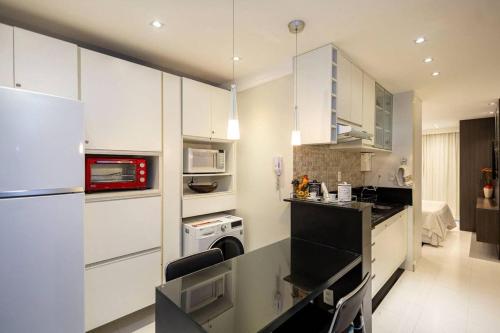 a kitchen with white cabinets and a black counter top at Estudio232 - Asa Sul in Brasília