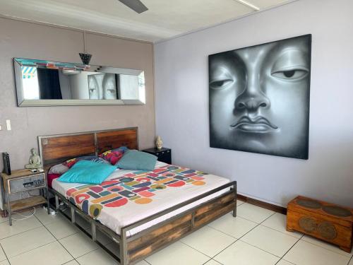 a bedroom with a bed with a picture of a face on the wall at Bleu Caraibe studio in Schœlcher