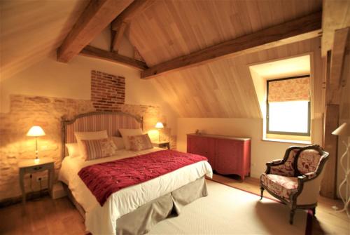a bedroom with a large bed and a chair at gîtes du Cheylard in Les Farges