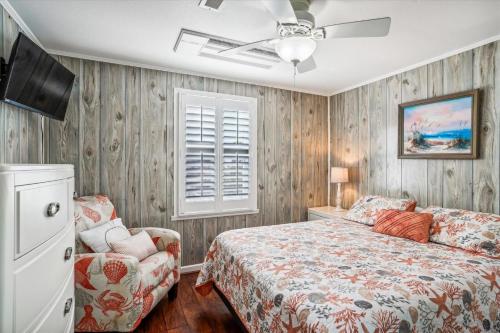 a bedroom with a bed and a fan and a chair at Sea Glass Shack in Kill Devil Hills