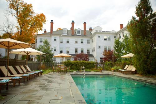 a pool with chairs and umbrellas in front of a building at The Red Lion Inn in Stockbridge