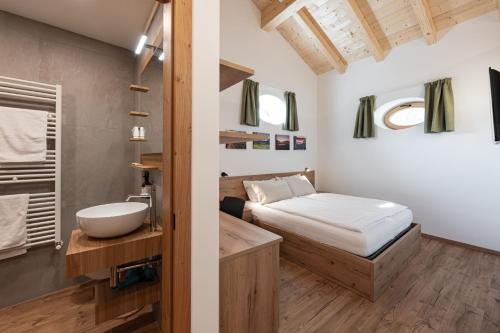 a bedroom with a bed and a bathroom with a sink at Palazzo Tamanini in Calceranica al Lago