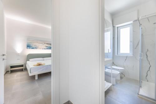 a white room with a bed and a bathroom at Appartamenti Mancaversa in Marina di Mancaversa