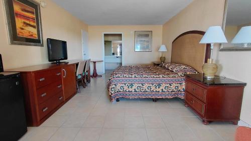a bedroom with a bed and a dresser and a television at Paramount Lakeside Inn & Suites in Lakeland
