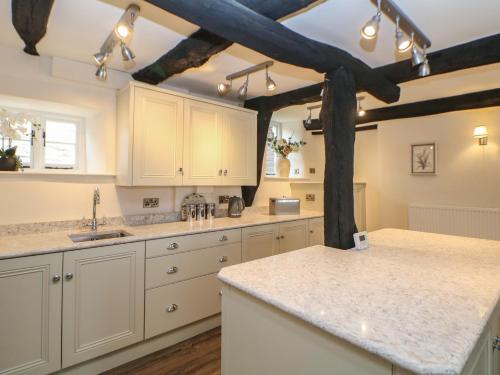 a kitchen with white cabinets and marble counter tops at The Toll Bar in Castleton