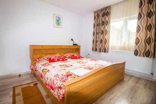 a bedroom with a wooden bed with red pillows at Cabana La Cucu in Vadu Moţilor