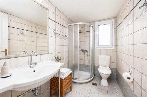 a bathroom with a sink and a shower and a toilet at Villa Bougainvillea in Vlachopoulátika