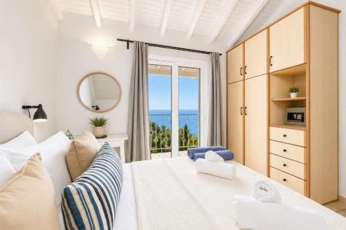 a bedroom with a white bed and a large window at Villa Bougainvillea in Vlachopoulátika