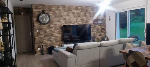 a living room with a couch and a clock on a brick wall at Le Mimosa in Cricquebœuf