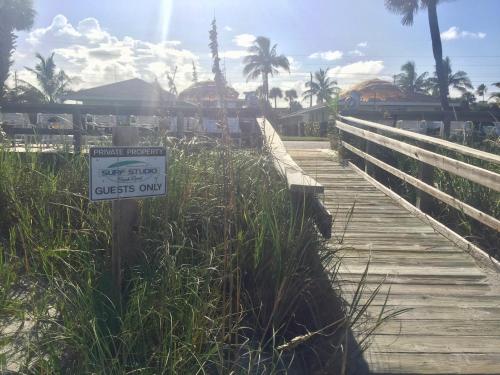 a sign on a wooden boardwalk near a beach at Surf Studio Beach Resort in Cocoa Beach