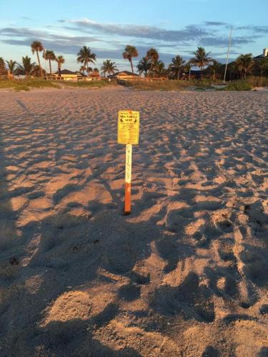 a warning sign in the middle of a sandy beach at Surf Studio Beach Resort in Cocoa Beach