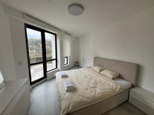 a bedroom with a large bed with a large window at View of the forest in Veliko Tŭrnovo