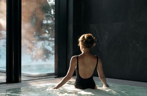 a woman sitting in a hot tub looking out a window at Chalets by Slow Tatry Boutique Resort&SPA in Zakopane