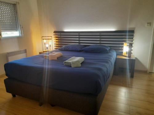 a bedroom with a blue bed with two towels on it at APPARTEMENT T2 proche de l'océan in Capbreton