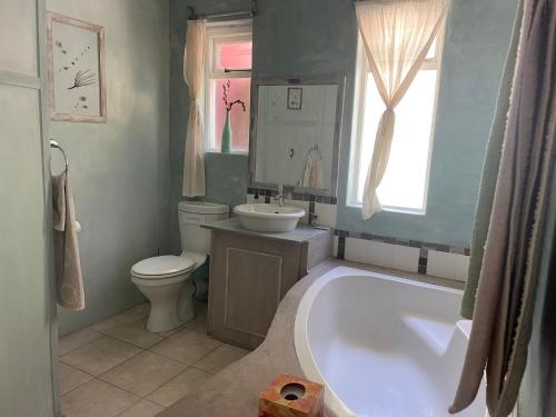 a bathroom with a tub and a toilet and a sink at Oceanview Sunrise Beach Villa in Rocklands