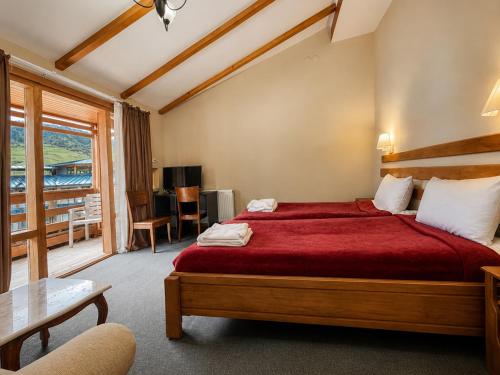 a bedroom with a large bed with a red bedspread at Hotel Old Seti in Mestia