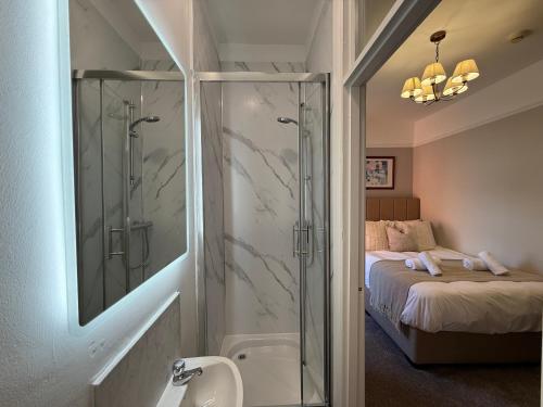 a bathroom with a glass shower with a bed at All Seasons Guesthouse in Belfast