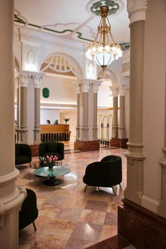 a lobby with chairs and a table and a chandelier at Palatinus Grand Hotel in Pécs
