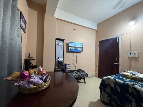 a living room with a table and a bed and a tv at Triveni Stays in Jorhat