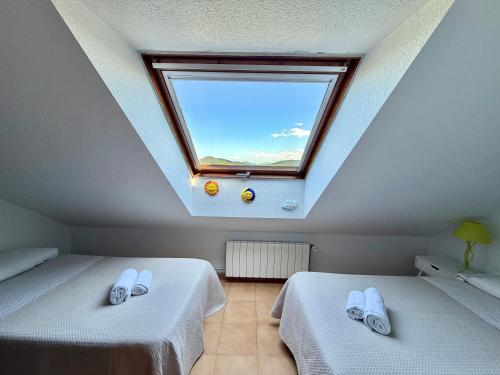 a attic room with two beds and a window at La Cometa de Ajo -12016 in Ajo
