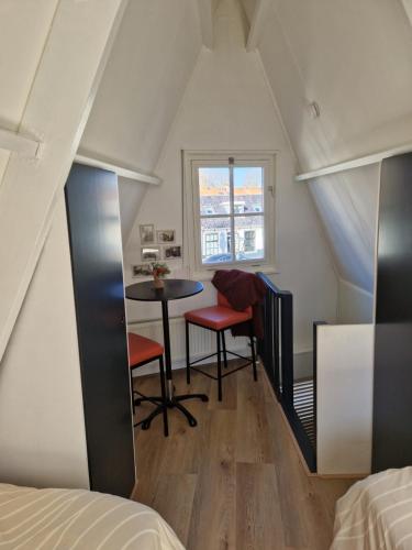 ein kleiner Raum mit einem Tisch und Stühlen auf einem Dachboden in der Unterkunft Bed & Breakfast De Punt in Monnickendam