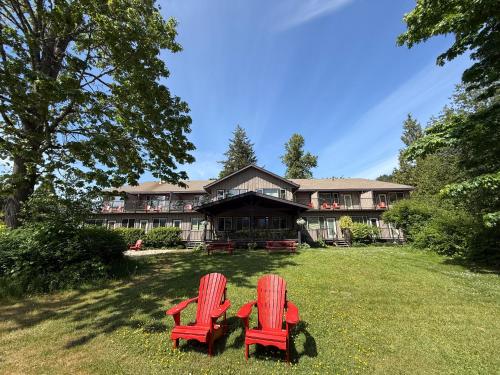two red chairs sitting in the grass in front of a house at Kiwi Cove Lodge in Ladysmith