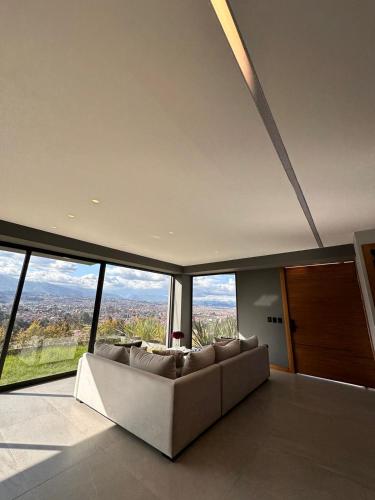 a living room with a couch and large windows at Casa con vista a cuenca in Cuenca