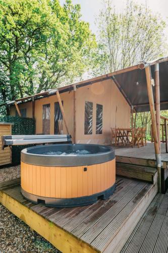 a house with a hot tub on a wooden deck at Kingfisher Safari Tent in Droitwich
