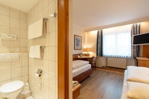 a hotel room with a bed and a bathroom at Parkhotel Crombach am Salingarten in Rosenheim