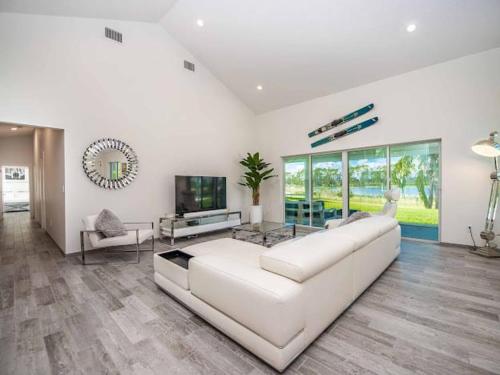 a living room with a white couch and a tv at SWISS 14 - Lake Stephanie in Clermont