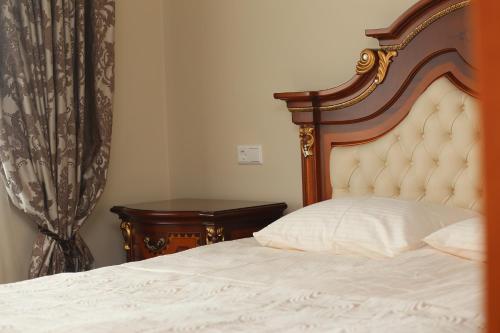 ein Schlafzimmer mit einem Bett mit hölzernem Kopfteil und einem Tisch in der Unterkunft Parko7 apartamentai in Plateliai