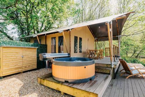 a large hot tub on a deck next to a house at Teal Safari Tent in Droitwich