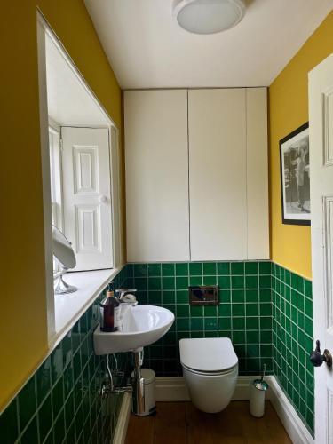 a green tiled bathroom with a toilet and a sink at Number 6 Narrow Water Castle in Warrenpoint