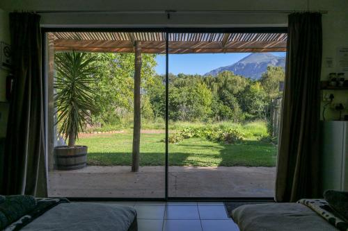 a room with a sliding glass door looking out at a yard at Canary Cottage in Greyton