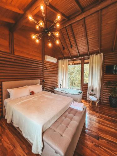 a bedroom with a large bed and a bath tub at Refugio Poço do Cânion in Alfredo Wagner
